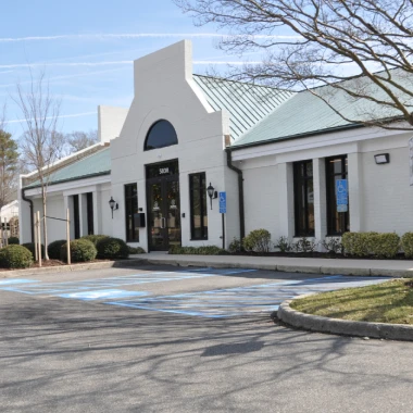 Front angle of Pappas Orthodontics featuring entrance, parking lot, trees, and clear sky.