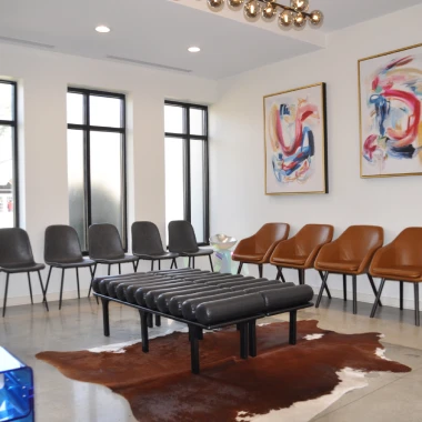 Patient waiting room at Pappas Orthodontics with stylish seating, artwork, and large bright windows.